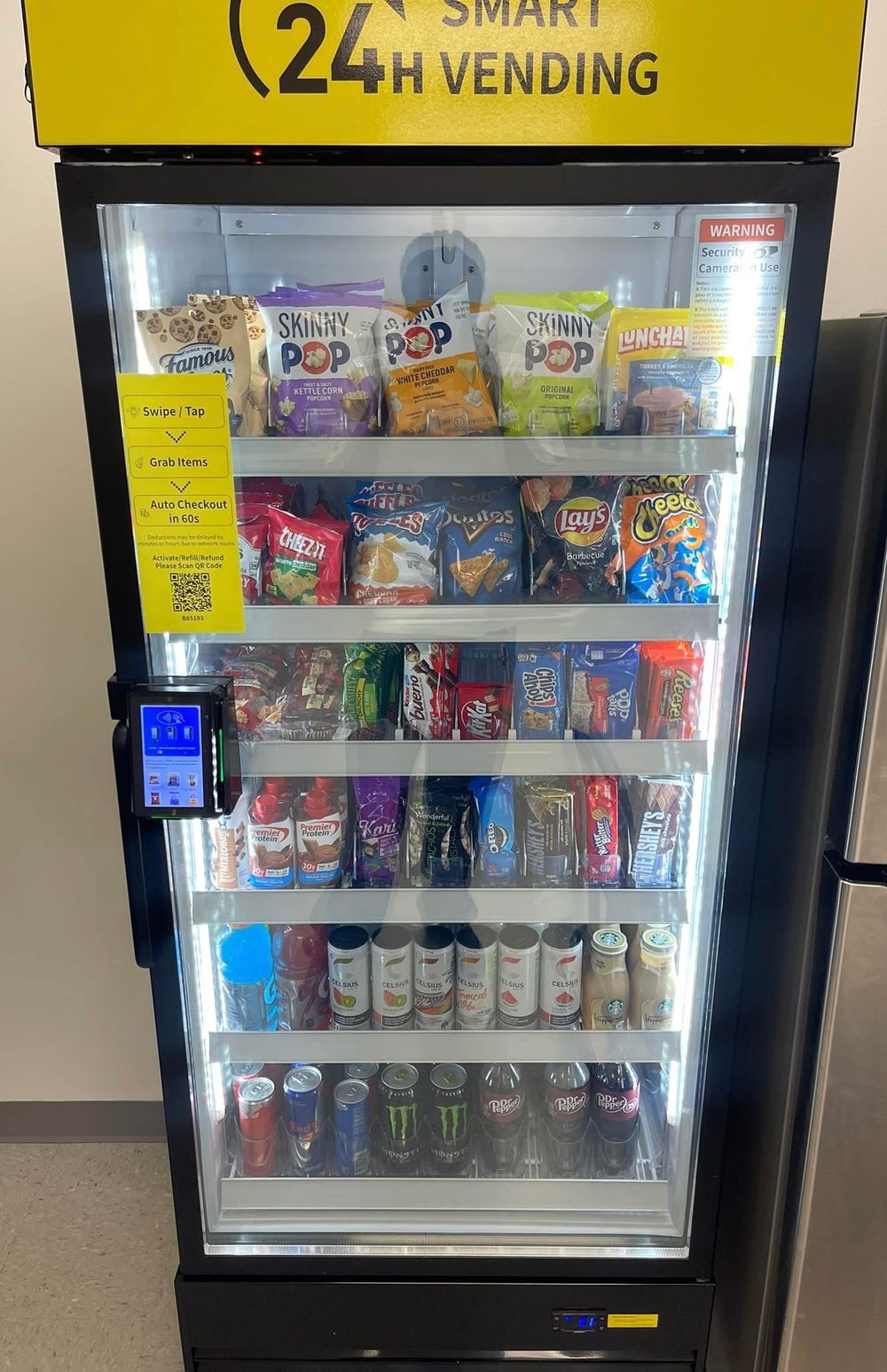 An NPC Snacks smart cooler stocked with drinks and snacks, with tap-to-pay checkout